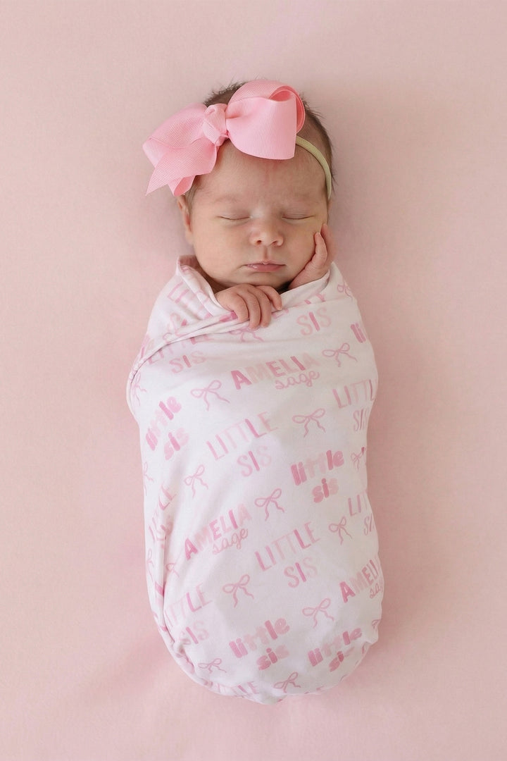 baby girl wrapped in little sis personalized swaddle blanket with pink bows