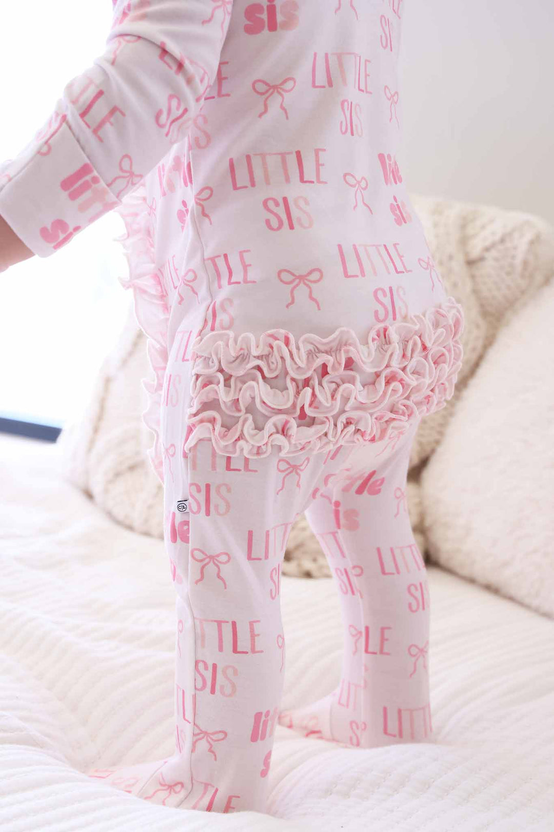ruffle bottom bamboo zipper footie pajama for girls in pink little sis block letter bow print 