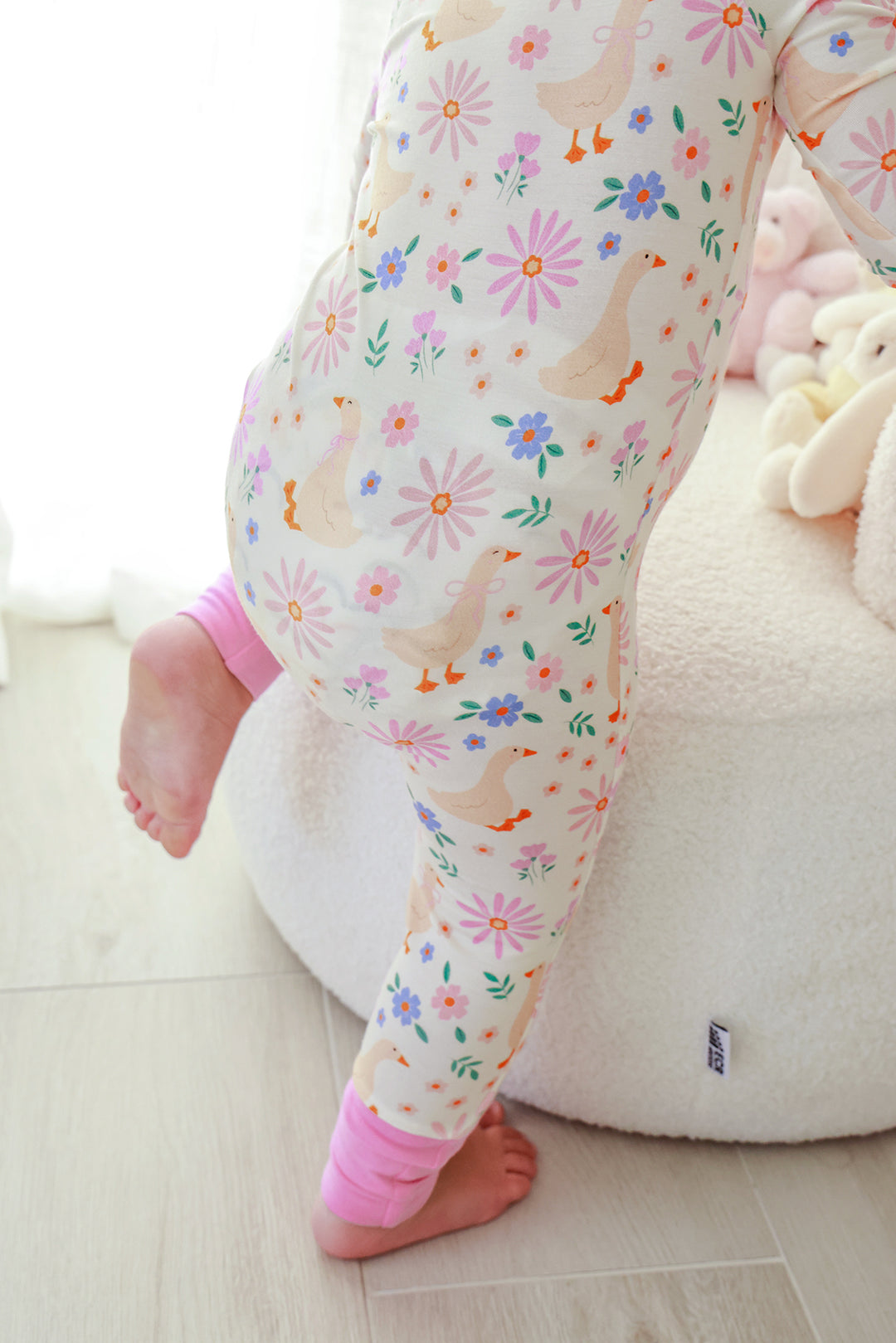 Close-up detail of the legs and open foot cuffs on the Lucy Goosy Convertible Zip Romper showing the floral duck print and pink convertible foot detail