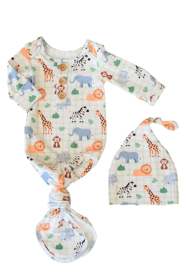 Flat lay of a Caden Lane knotted gown with three wooden buttons and a matching knot hat in a Wild Child print featuring giraffes, zebras, elephants, lions, hippos and monkeys on cream plaid.