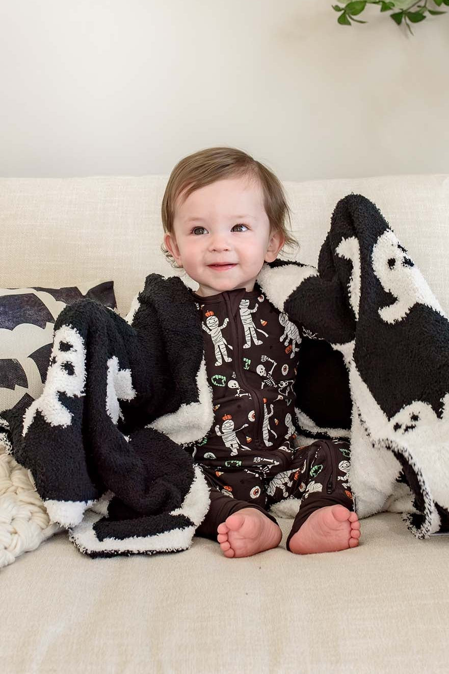 boy sitting on chair in mummy pajamas with ghost cuddlelane blanket wrapped around his shoulders