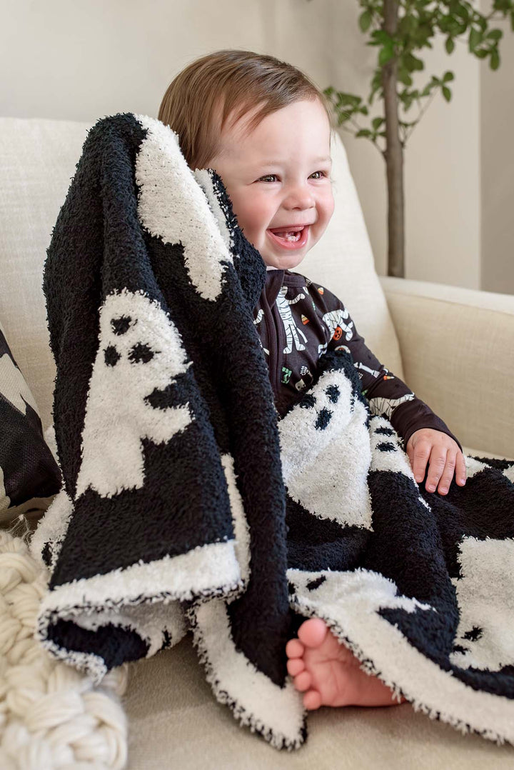 boy sitting on chair with ghost cuddlelane blanket wrapped around him