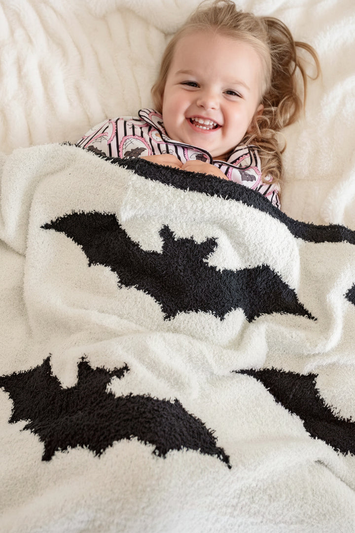 girl laying on bed in bat cuddlelane microfiber blanket 