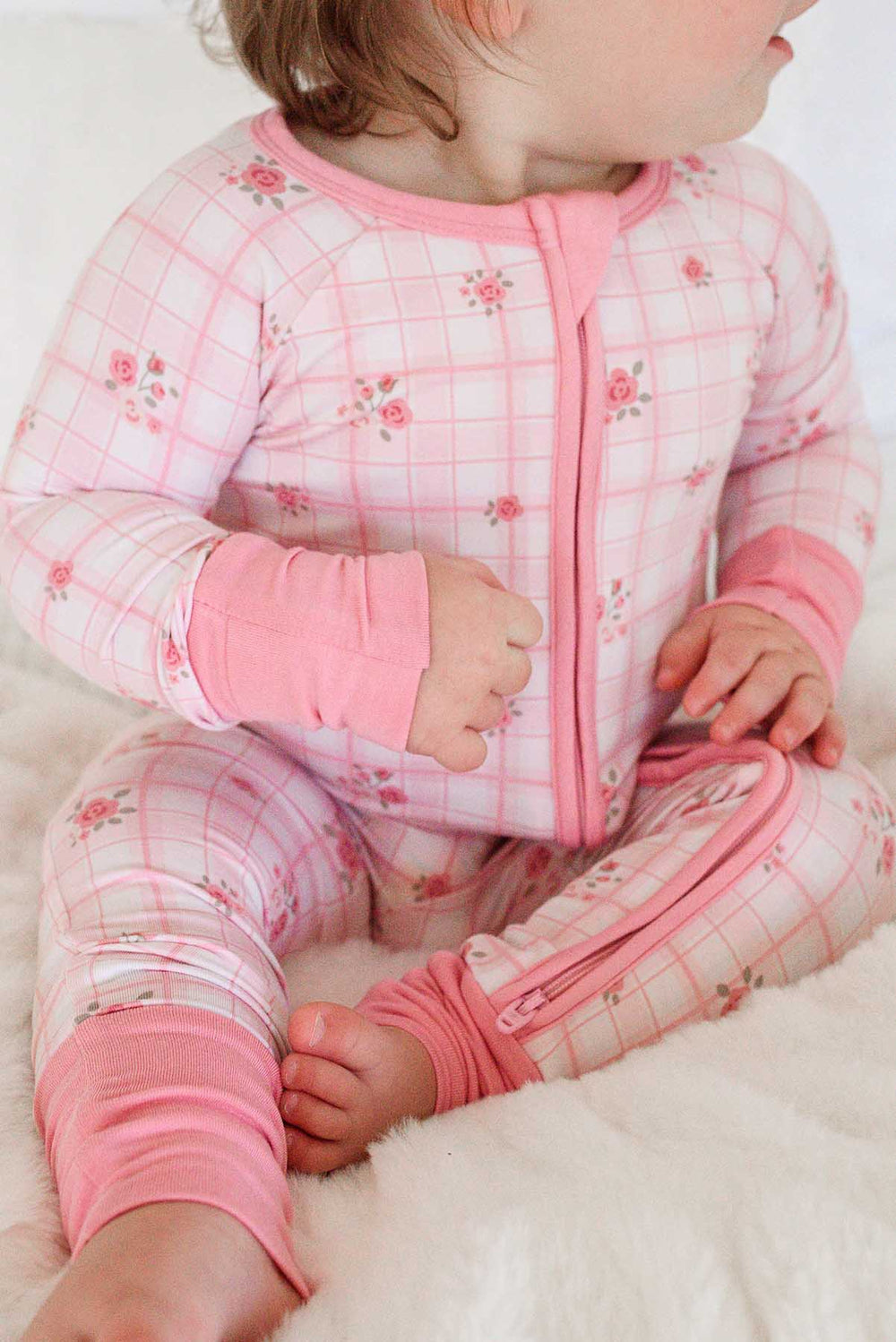 Baby sitting showing fold-over footie detail on plaid romper