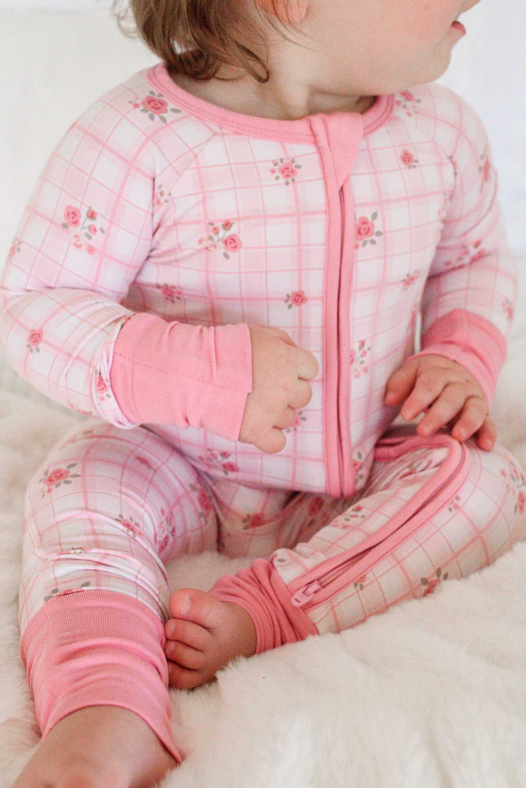 Baby sitting showing fold-over footie detail on plaid romper