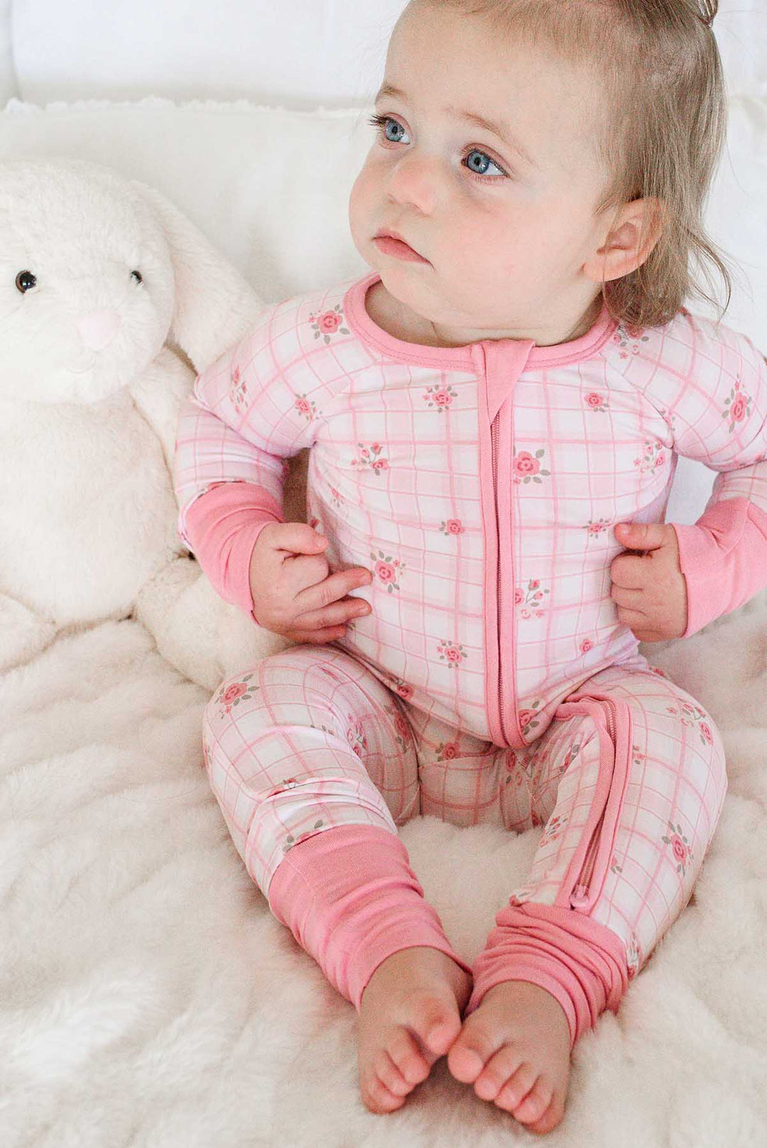 Baby sitting on plush blanket in Primrose Plaid romper near bunny toy