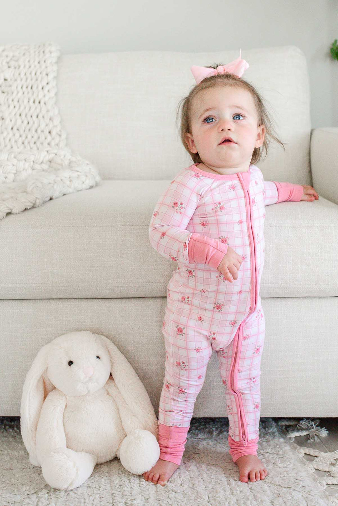 Curious toddler standing at couch in Primrose Plaid romper