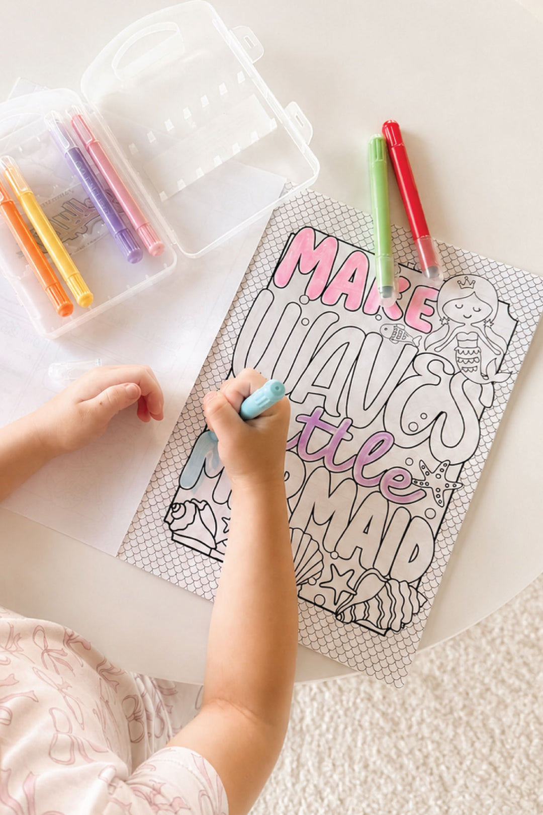 Child coloring the "Make Waves Little Mermaid" title page from the Caden Lane Magical Mermaid coloring book with Gellypop gel crayons.