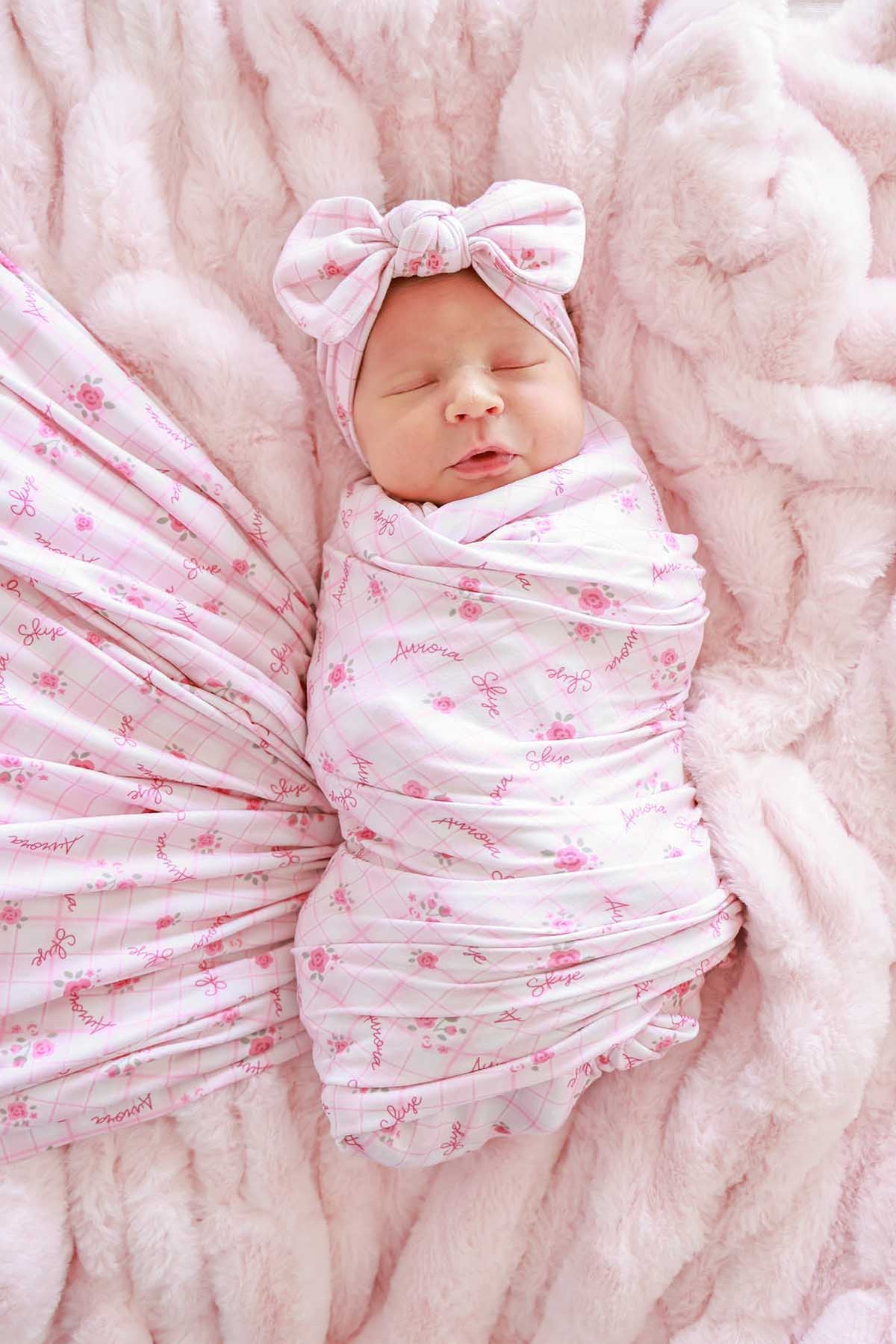 Newborn swaddled in personalized Primrose Plaid blanket with bow headwrap