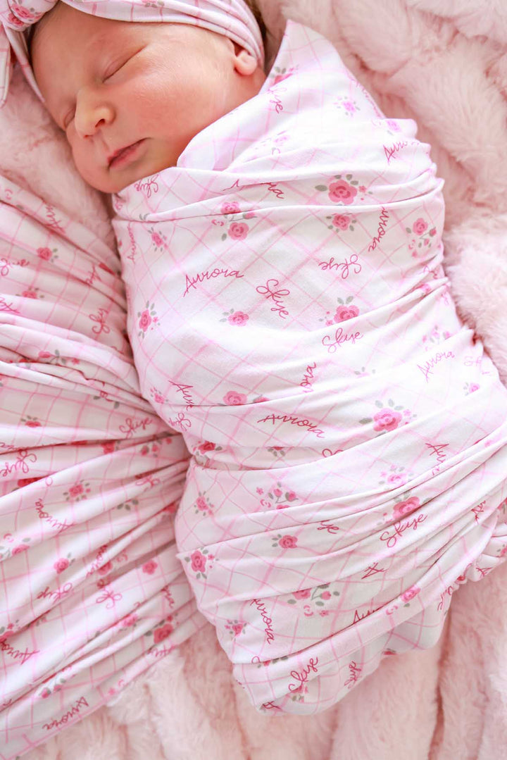 Close-up of sleeping newborn swaddled in personalized print blanket