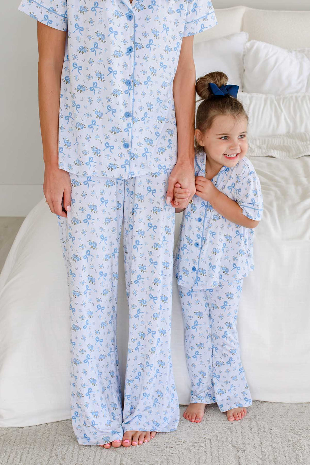 mom and daughter holding hands standing in front of bed in tied in blooms lounge sets
