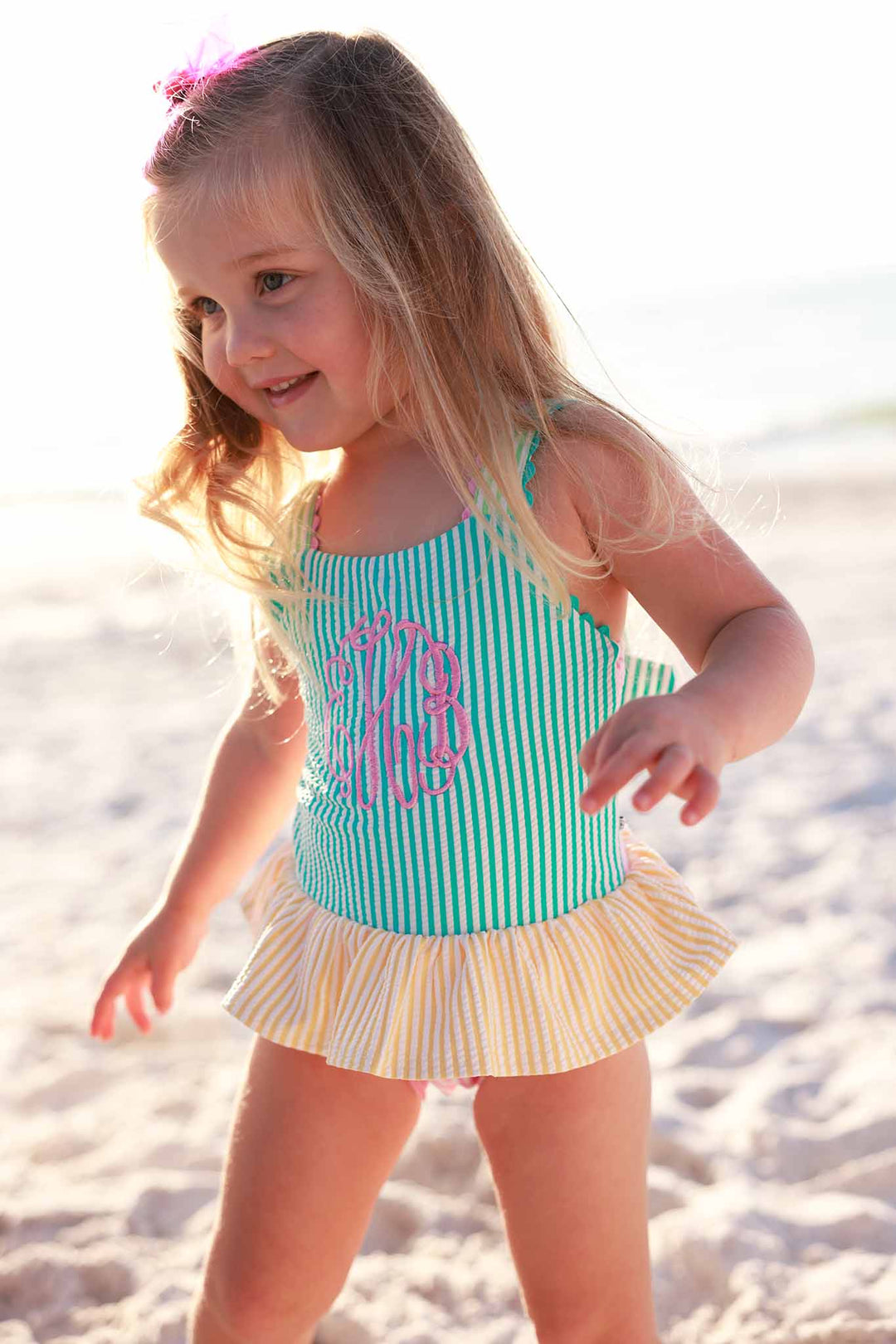 girl walking on the beach in multicolor seersucker one piece swimsuit with monogram