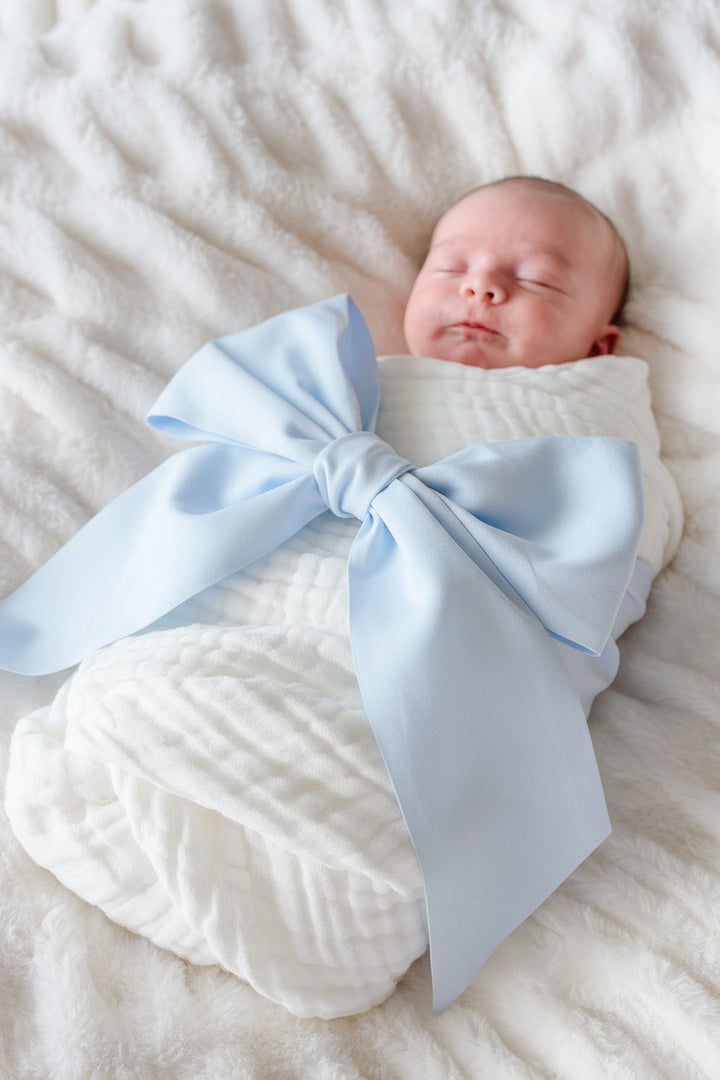 baby wrapped in light blue bow sash
