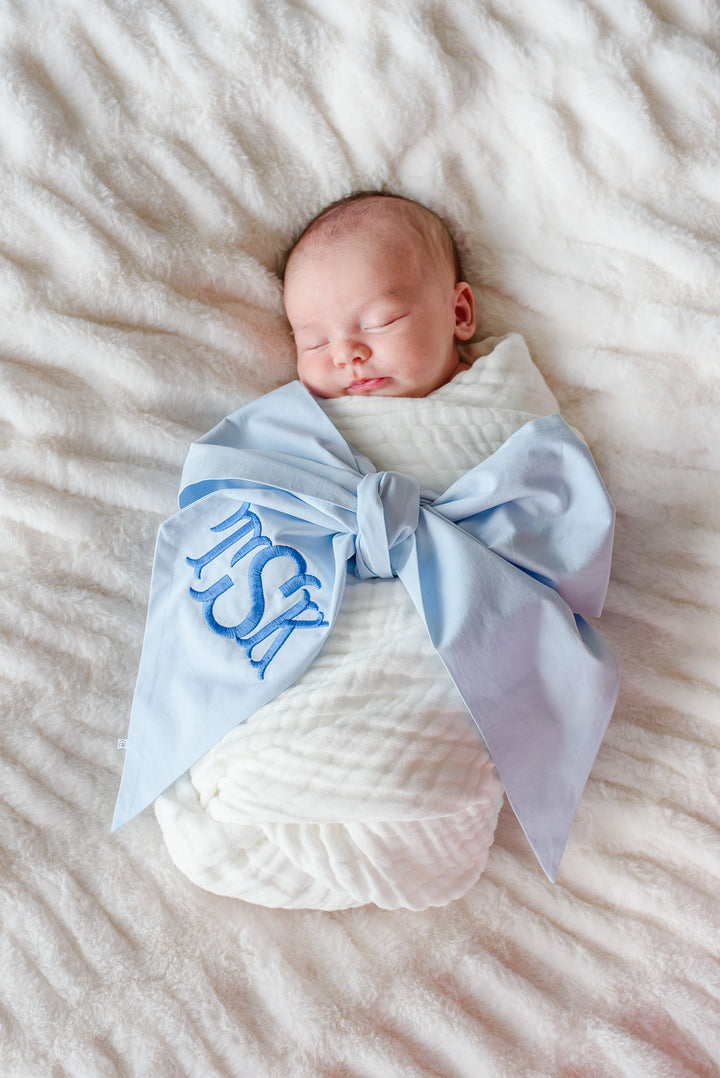 sleeping baby wrapped in light blue monogrammed bow sash