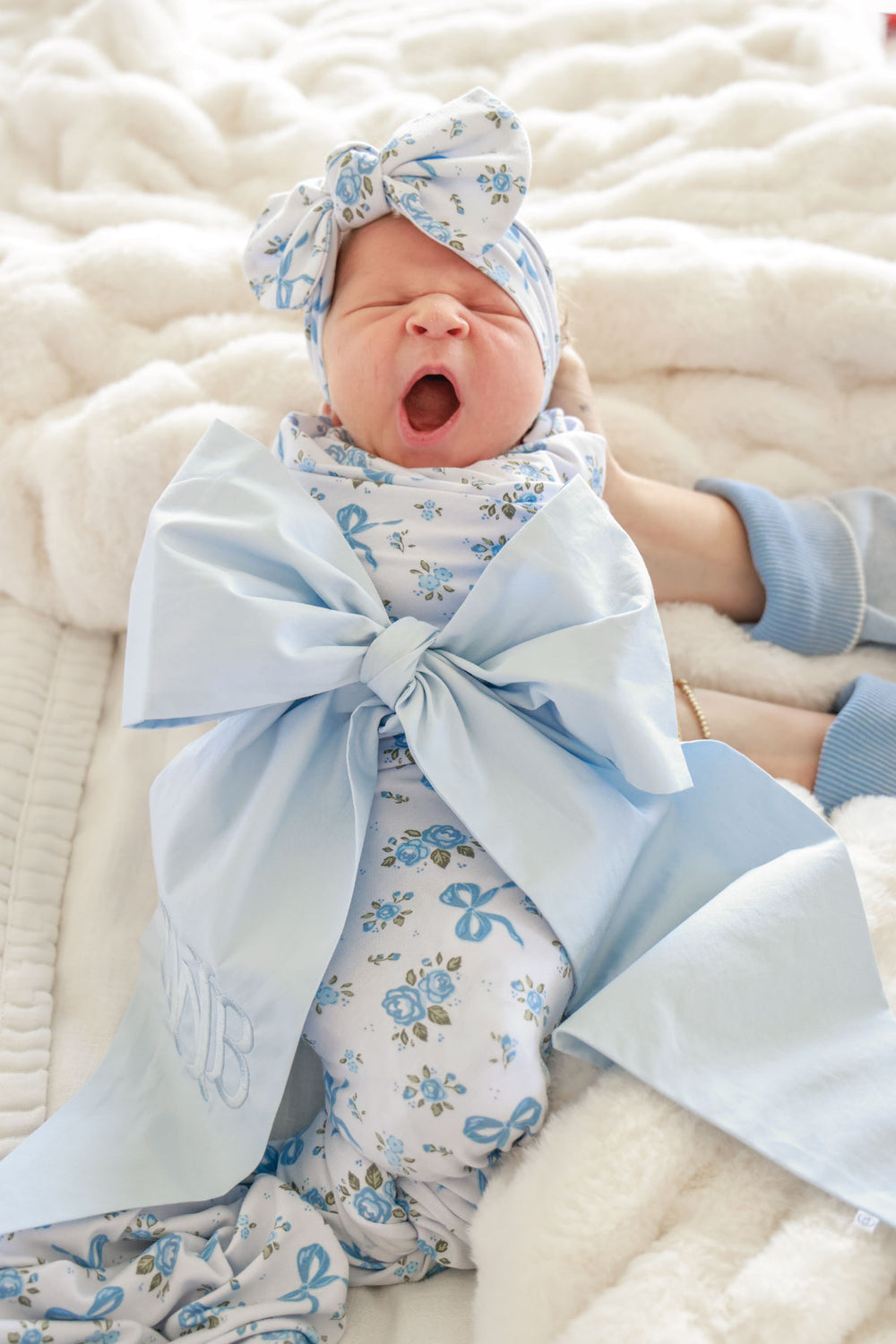 yawning girl in light blue newborn sash
