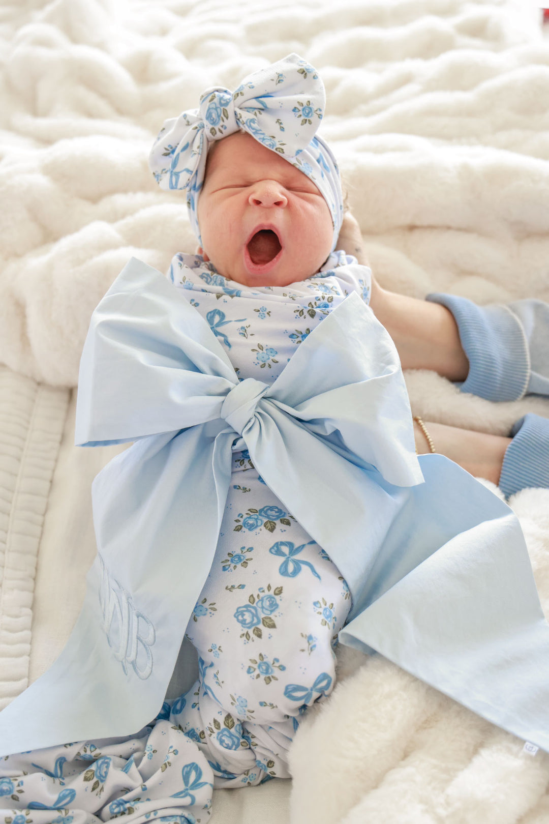 yawning girl in light blue newborn sash