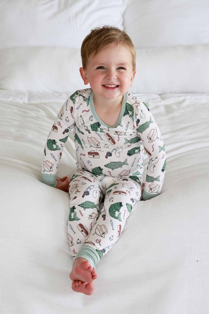 Toddler smiling while sitting showing the full front of the Off The Hook two piece pajama set