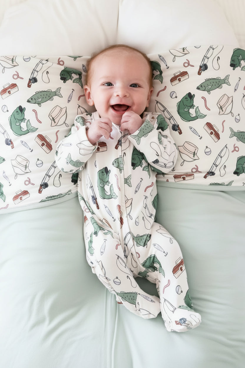 Newborn lying on fishing themed blanket wearing the Off The Hook zipper footie with fishing print