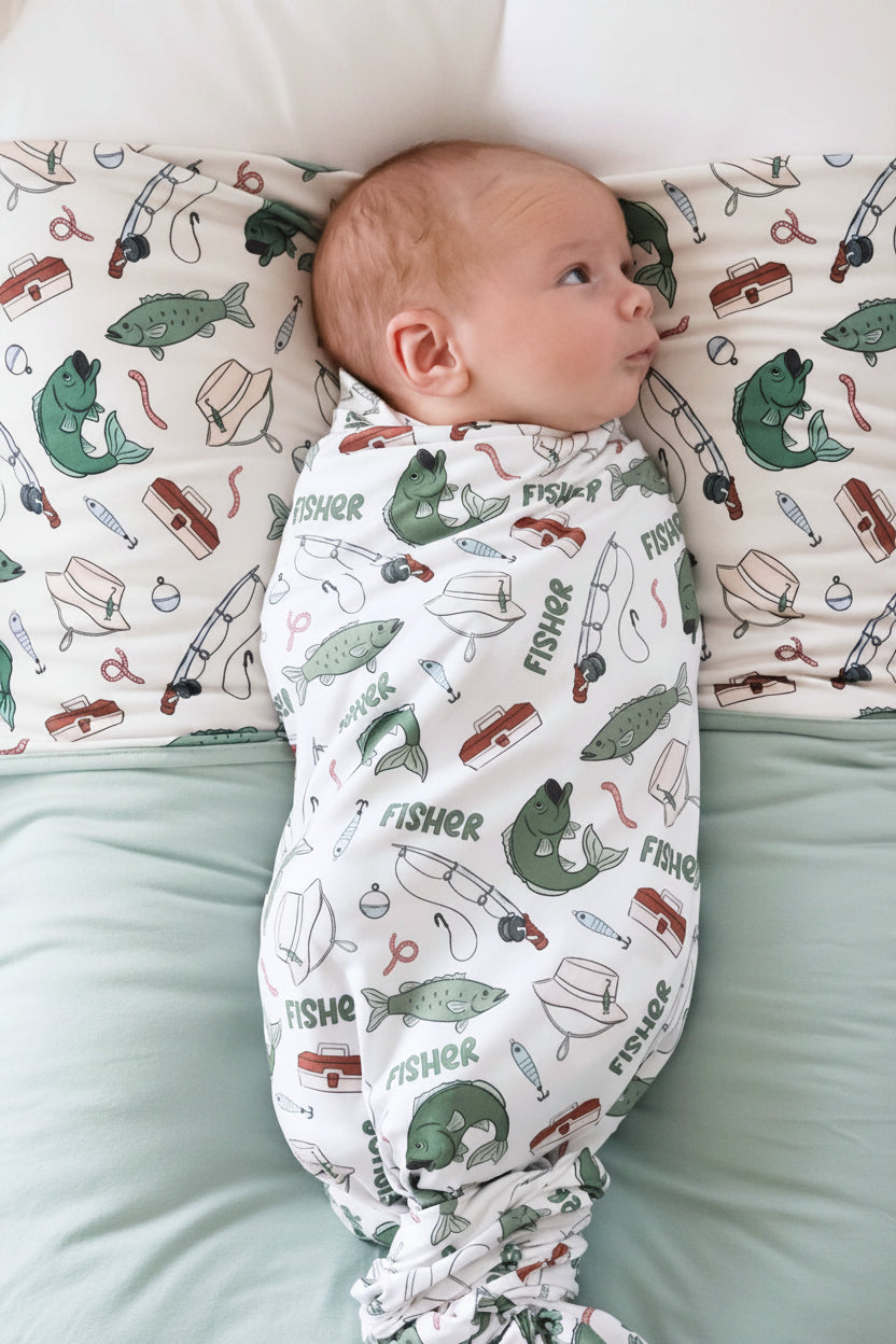 Newborn wrapped in the personalized Off The Hook swaddle blanket with fishing themed print and custom name