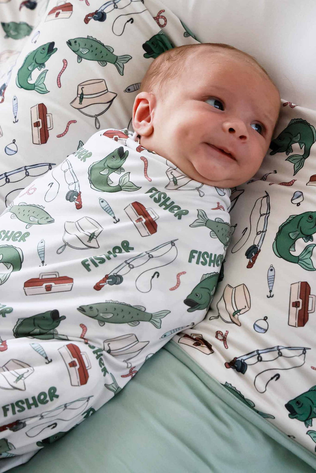Close-up of newborn laying in the personalized Off The Hook swaddle blanket with fishing themed print