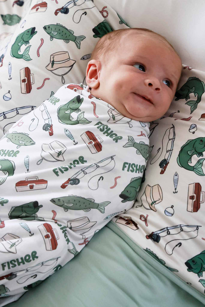 Close-up of newborn laying in the personalized Off The Hook swaddle blanket with fishing themed print