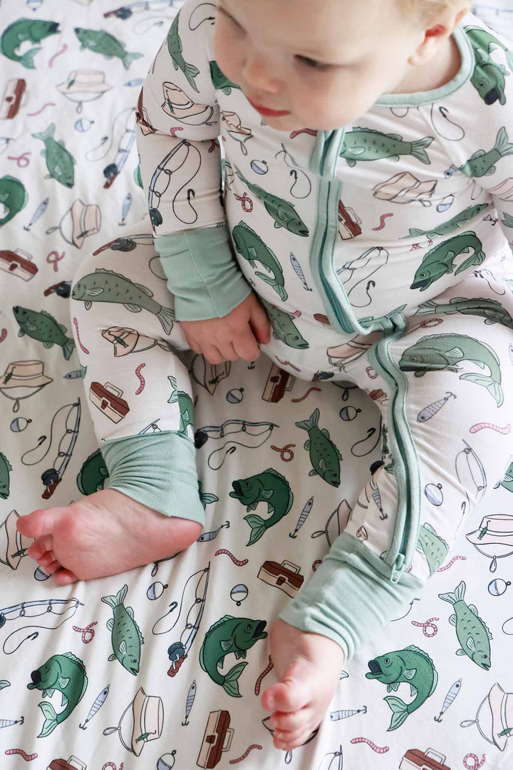Overhead view of baby lying down in the Off The Hook convertible zip romper on fishing themed blanket