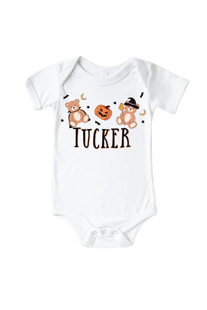 Caden Lane white baby onesie with Halloween-themed graphics and the name 'Tucker' on a white background