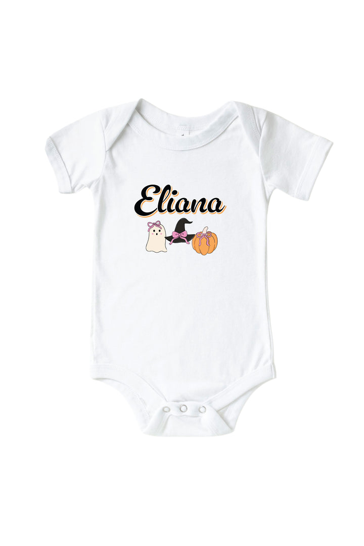 A white short-sleeve baby bodysuit with a custom graphic print on the chest. The print features the name 'Eliana' in black cursive, accompanied by a small cartoon illustration of a white cat wearing a black witch hat next to an orange pumpkin.