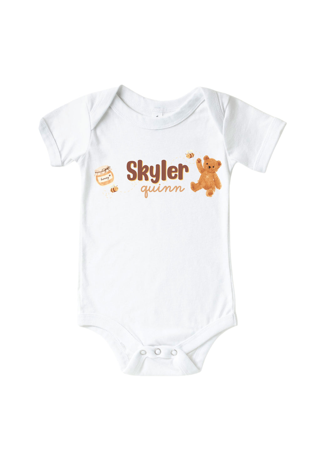 White baby onesie personalized with the name 'Skyler Quinn' alongside a honey jar, bees, and teddy bear graphic, laid flat on a white background