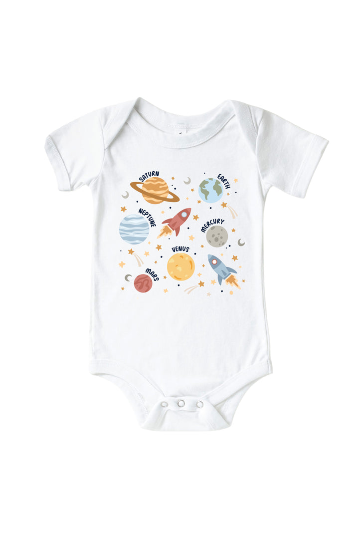 Flat lay of a Caden Lane white short-sleeve bodysuit with a Stellar Snuggles graphic featuring a rocket, Saturn, Earth, and stars, reading “Nathan.”