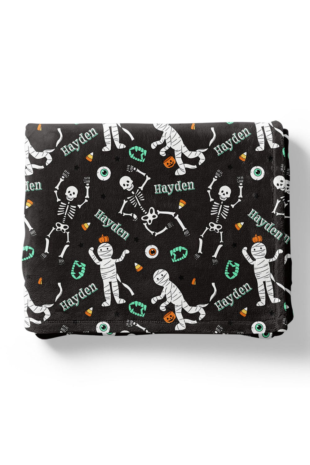 Folded black blanket personalized with the name 'Hayden' and Halloween skeleton and mummy graphics on a white background.