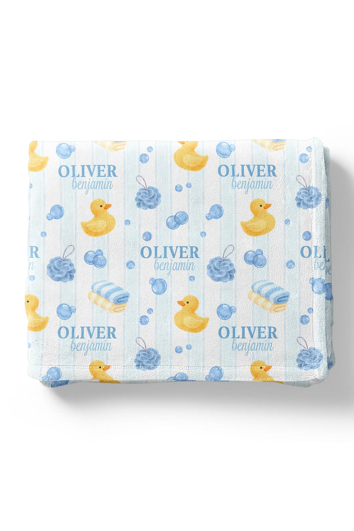 Young boy wrapped in blue Bubble Duckies personalized blanket with yellow rubber duck print and custom name in cozy pose
