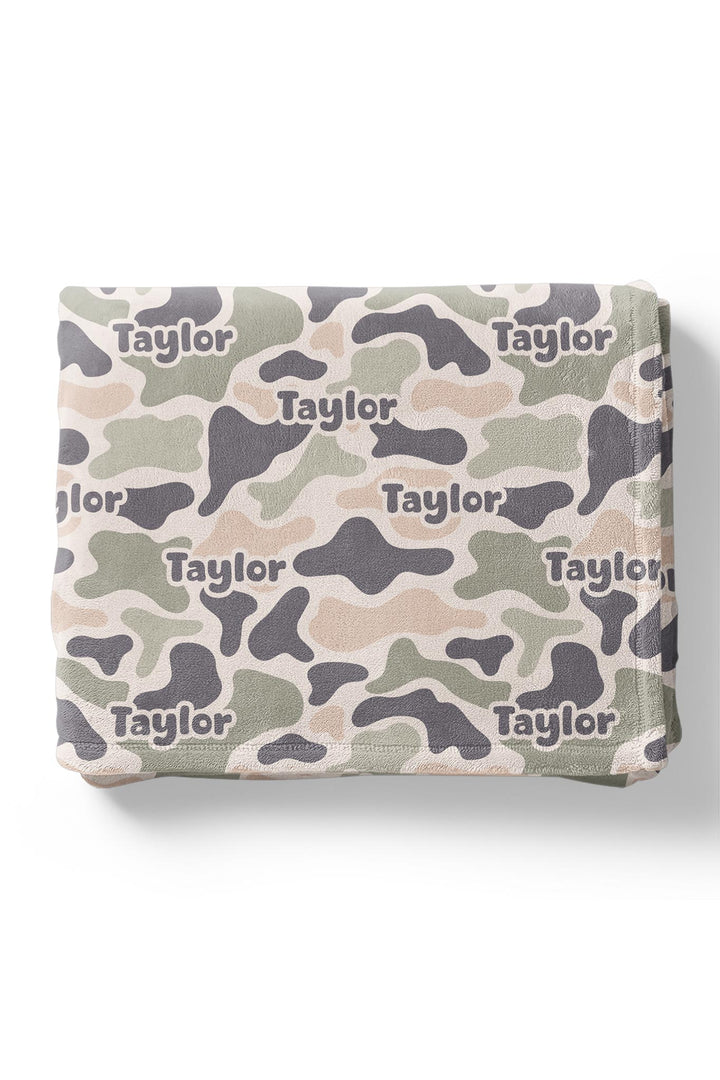 Personalized camo cutie kids blanket folded flat showing camo print in olive, tan, and gray with custom name repeated
