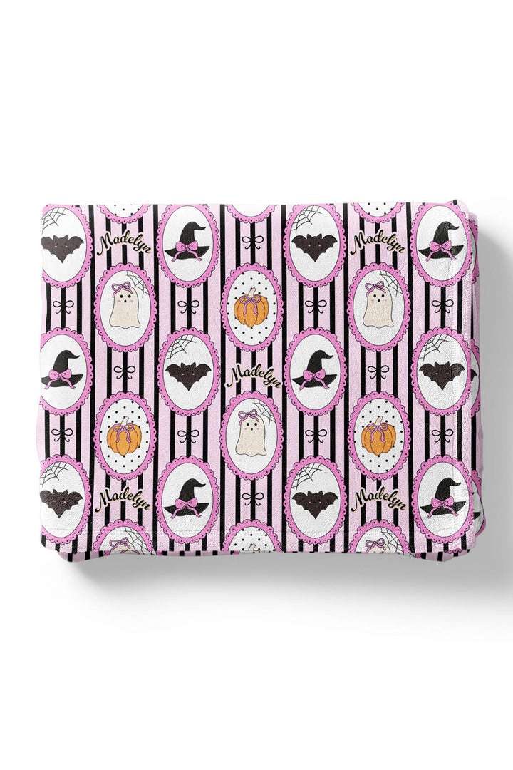Folded fabric with Halloween-themed pattern featuring pumpkins, bats, and witches' hats on a white background.