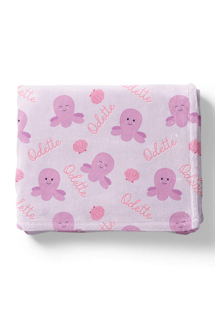 toddler wrapped in personalized sea snuggles kids blanket in lavender plush with purple octopus and seashell print and custom name in pink script