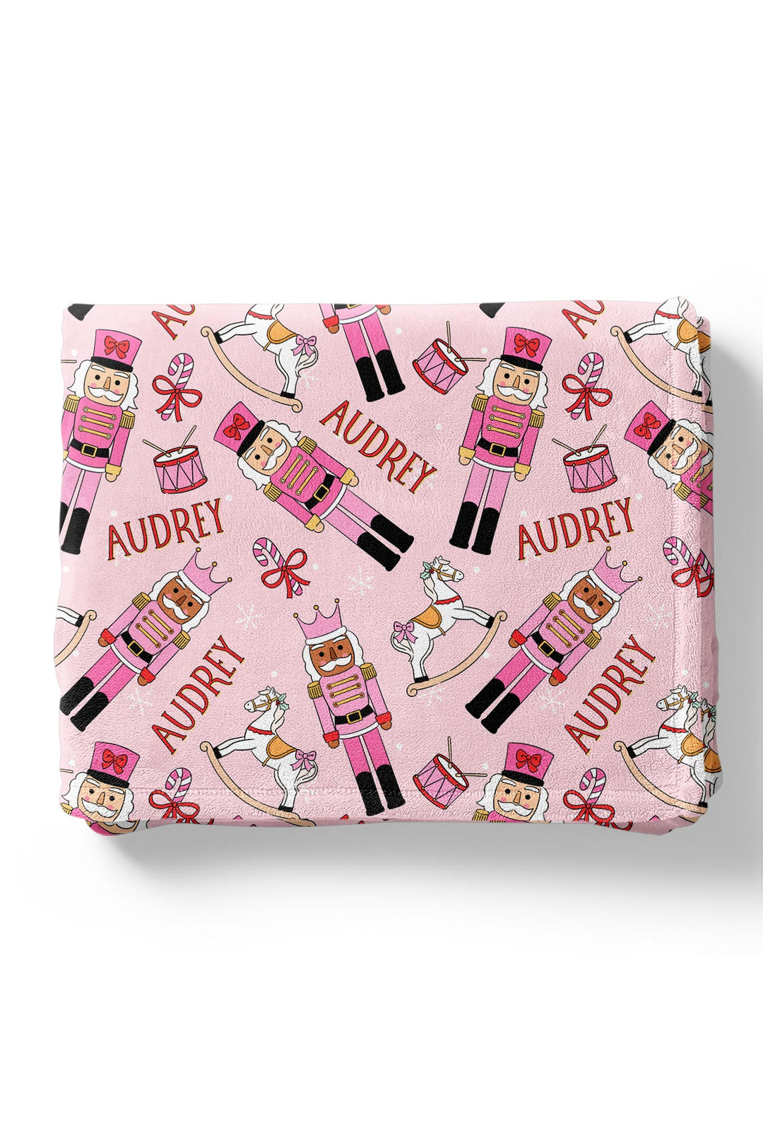 Personalized Caden Lane Christmas blanket featuring pink nutcrackers, rocking horses, drums, bows, snowflakes, and a custom child’s name.