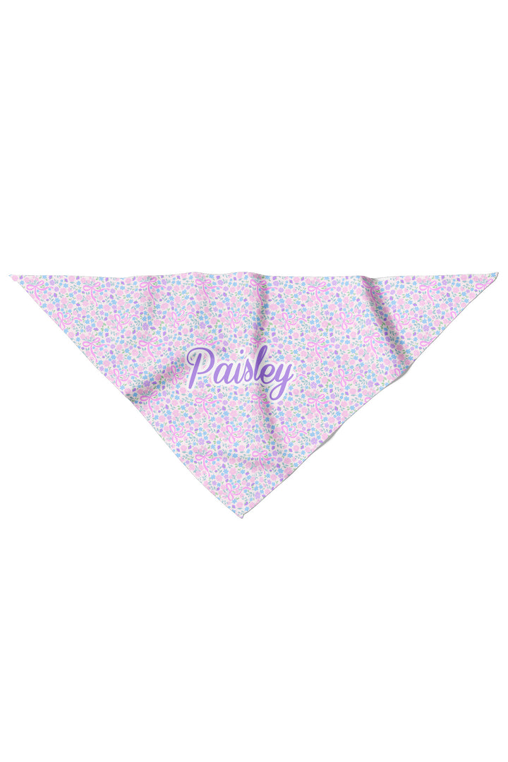 Personalized pet bandana in the Ribbon Garden print — a soft pink and lavender floral pattern — displayed flat in a triangle shape, personalized with the name "Paisley"