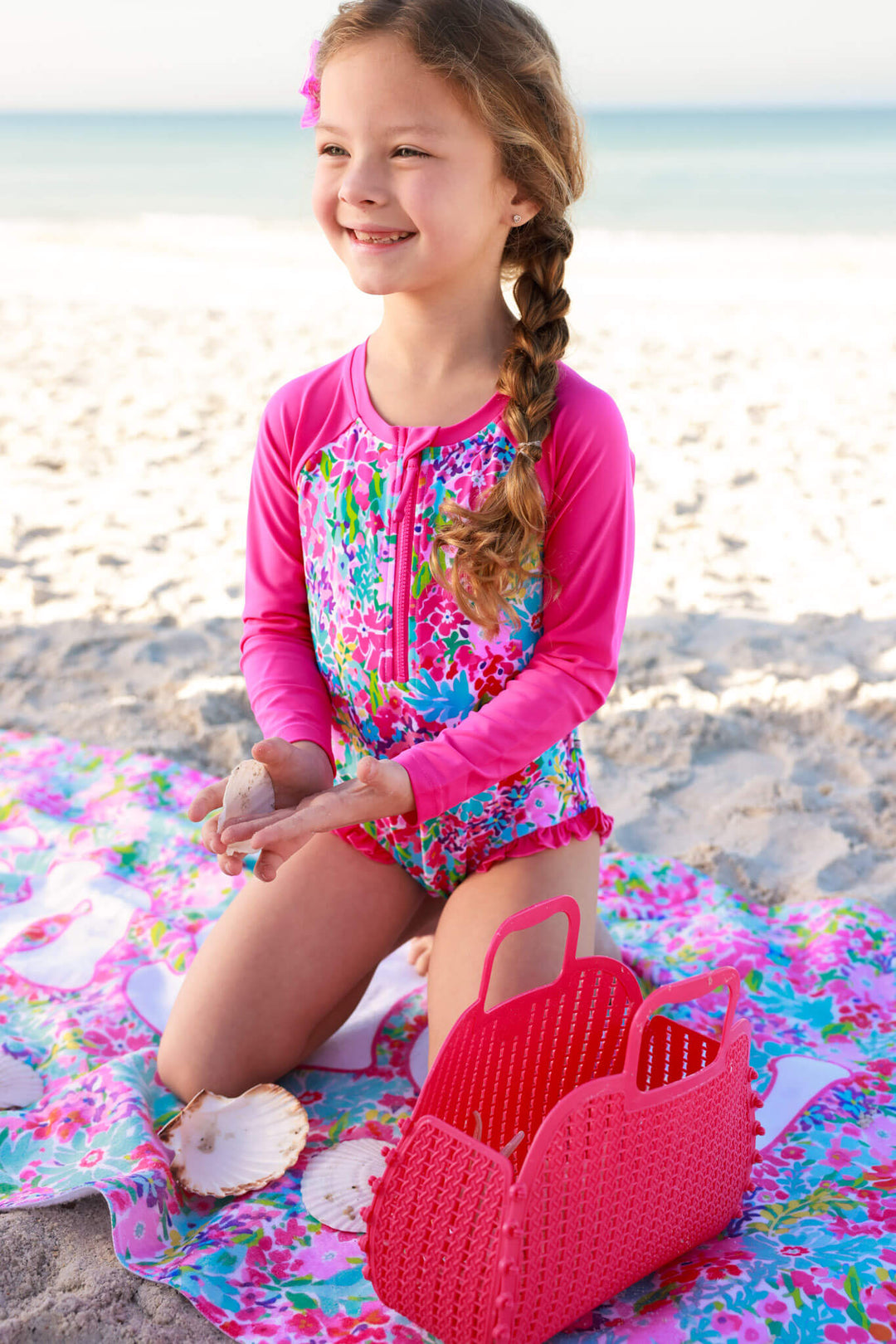 girl kneeling on beach towel in petal splash rash guard 