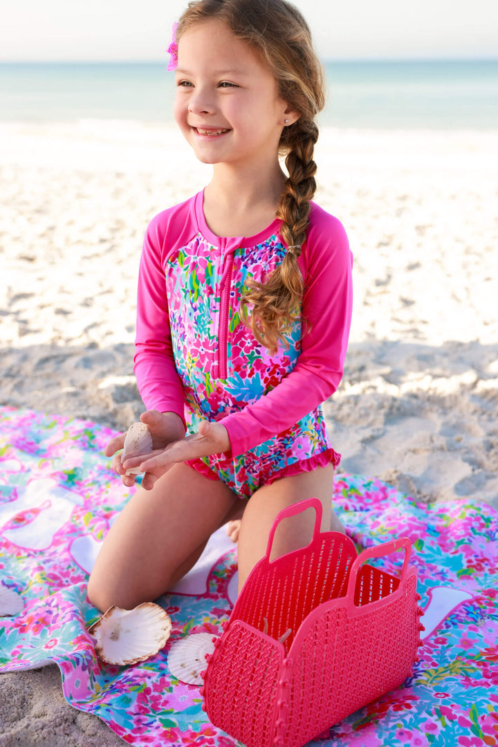 girl kneeling on beach towel in petal splash rash guard 