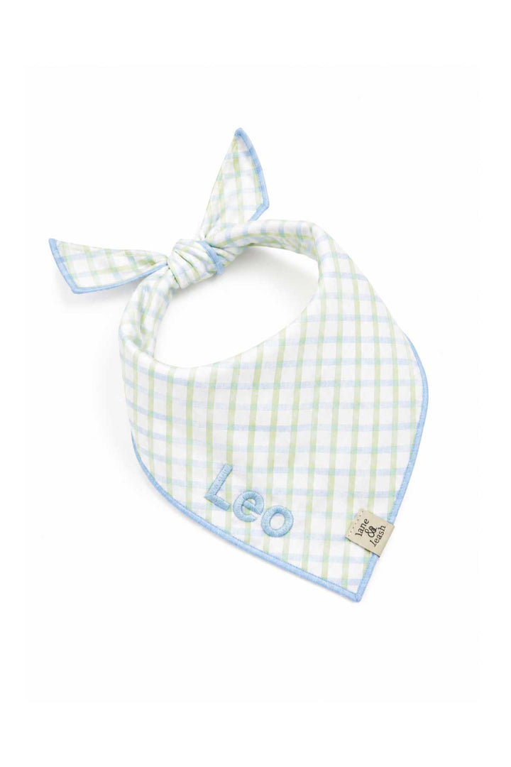 Embroidered pet bandana in green and blue picnic plaid tied in a bow, with the name "Leo" embroidered on the front panel