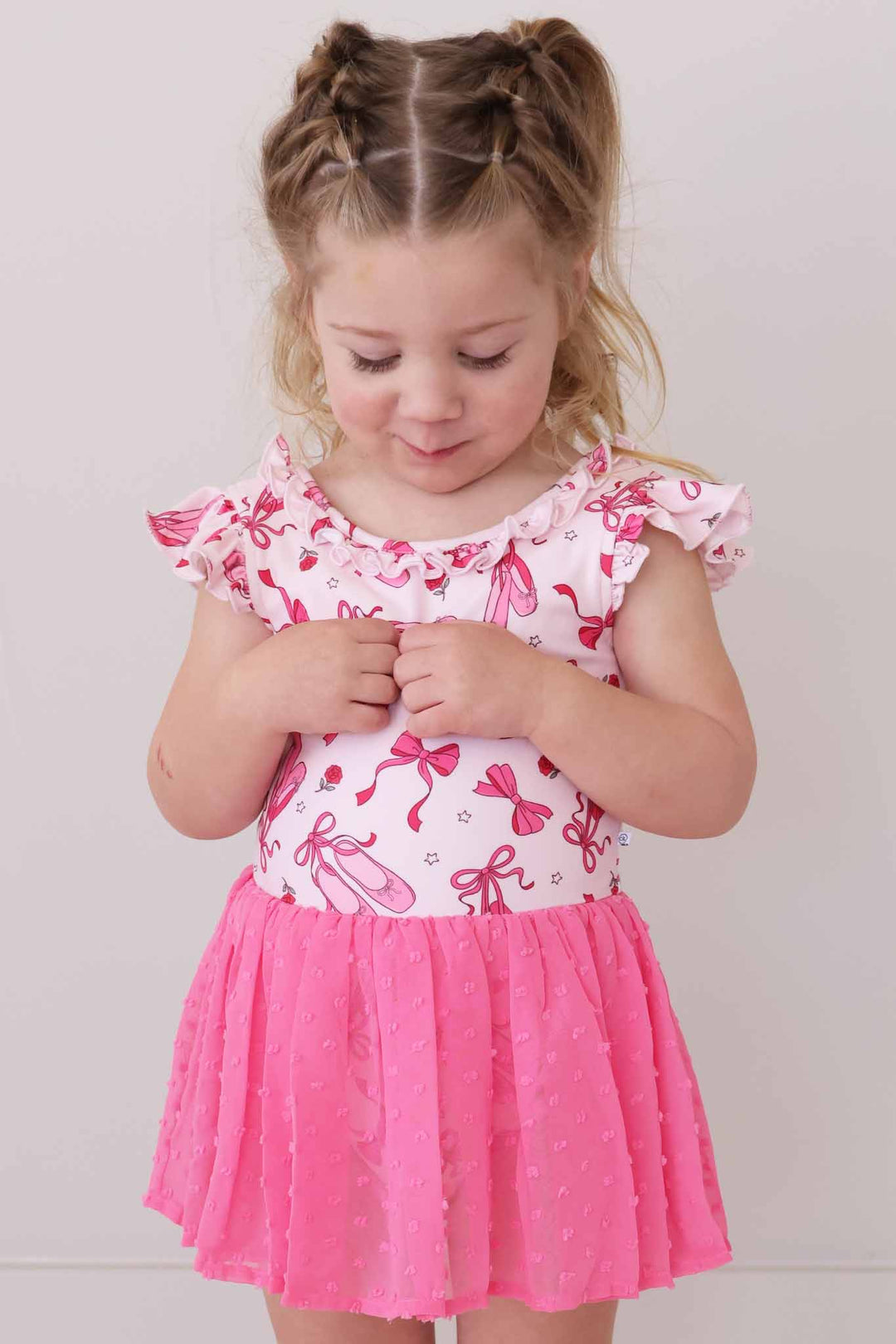 girl looking down in pink pirouette leotard with hot pink skirt 