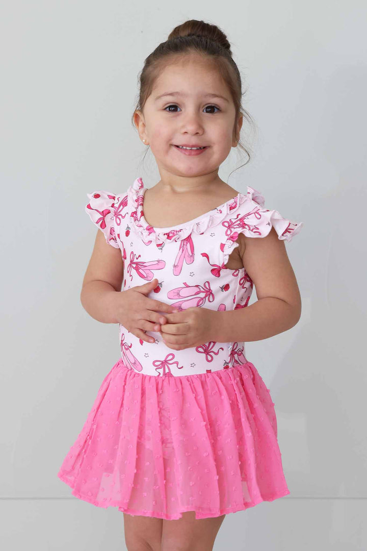 smiling girl in pink ballet shoe and bow tulle skirt leotard