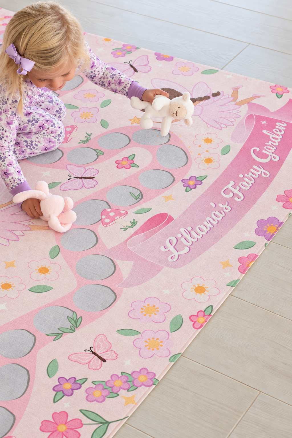 Girl playing on a personalized Caden Lane fairy garden playroom rug featuring pink pathways, flowers, butterflies and magical fairies.
