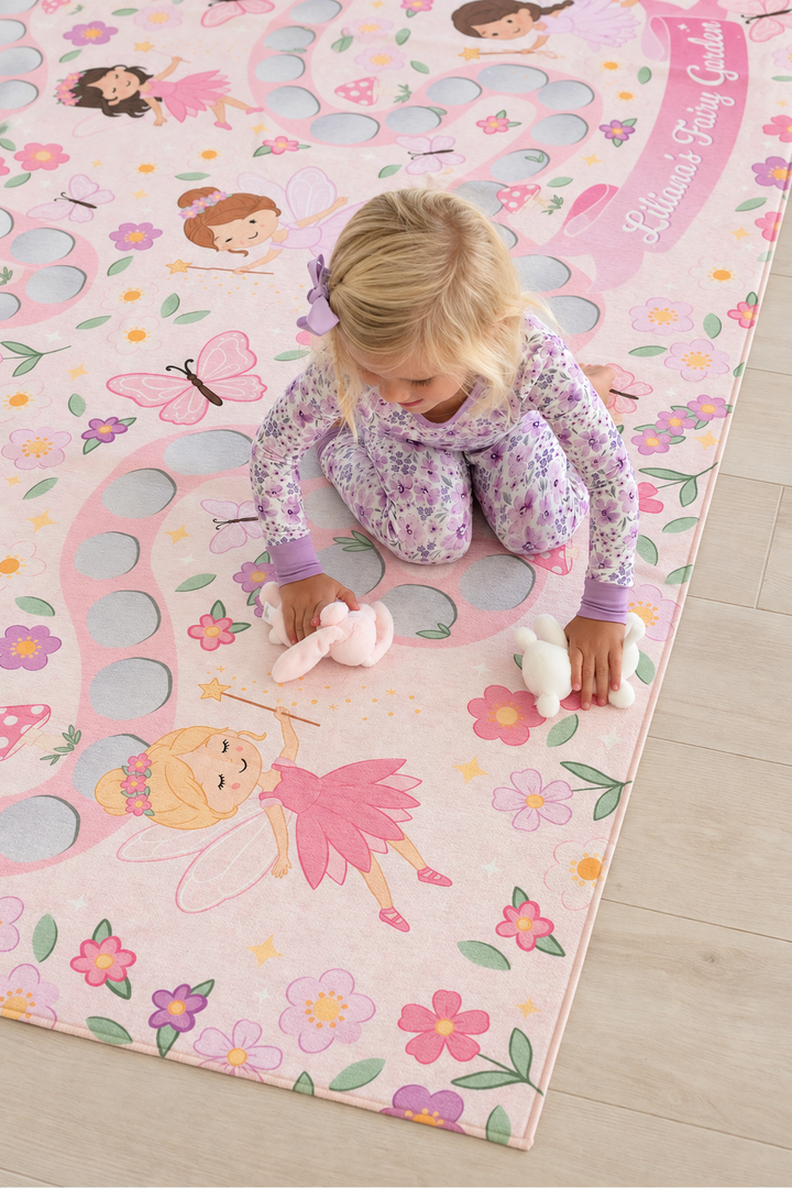 Overhead view of a girl playing on a personalized Caden Lane fairy playroom rug with pink pathways, flowers and whimsical garden fairies.