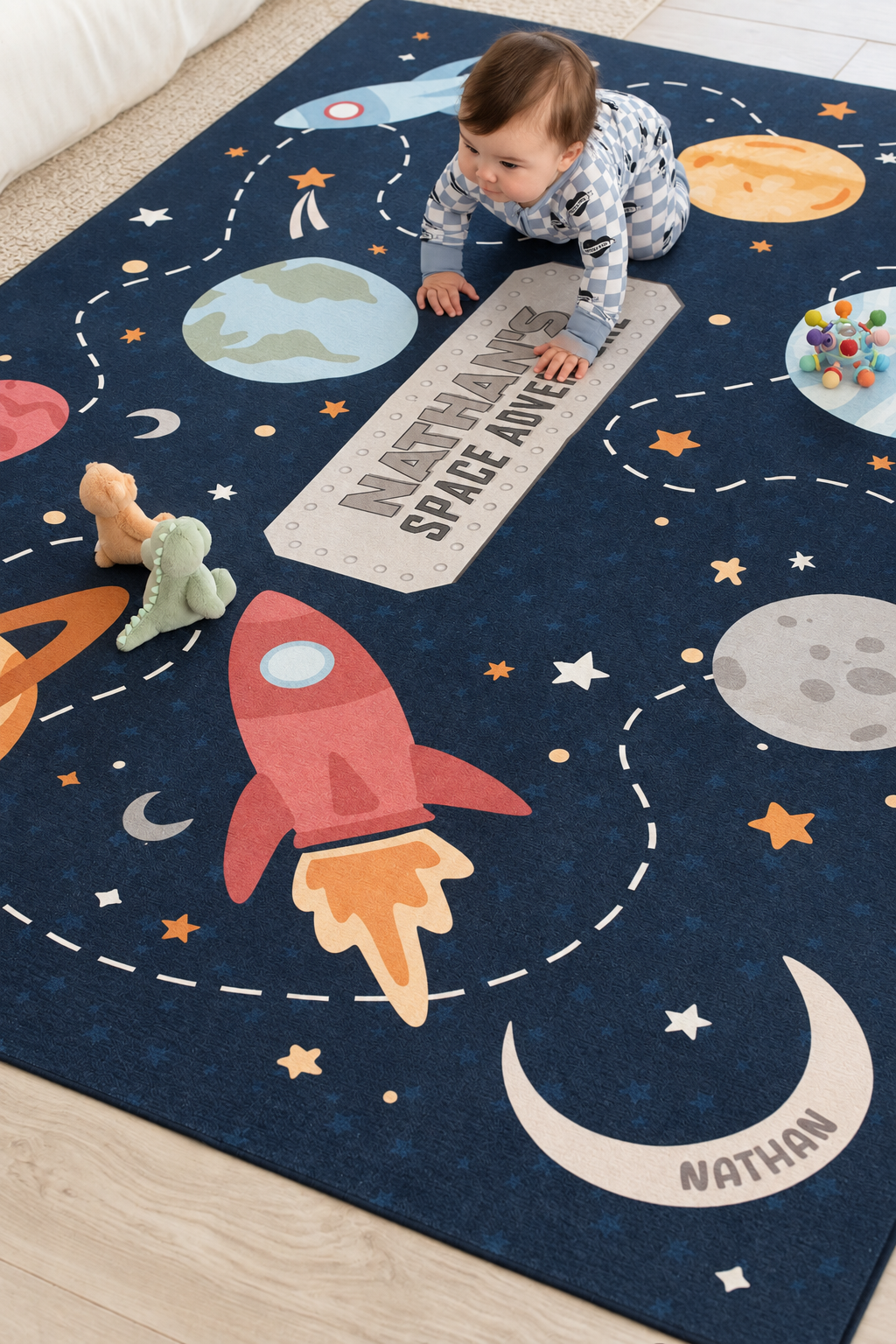 Baby playing with plush toys on a personalized Caden Lane outer space playroom rug with planets, stars and a red rocket ship.