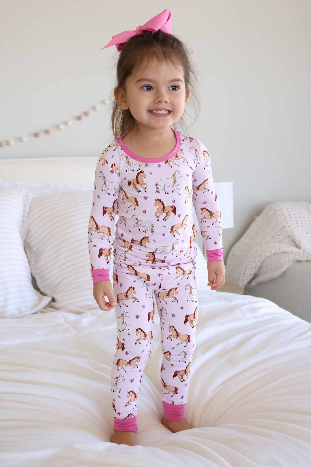 girl standing on bed in pony club pink two piece pajama set 