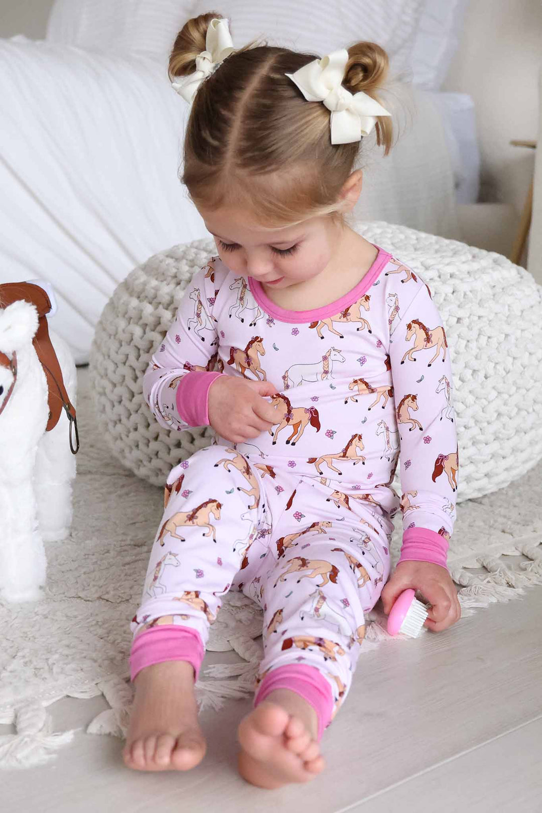 girl sitting on floor in girly pony two piece pajama set 