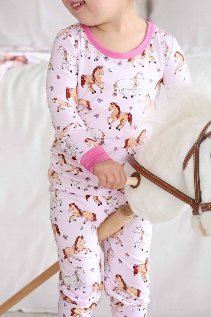 girl riding on a stick horse in girly horse and flower pajama set 