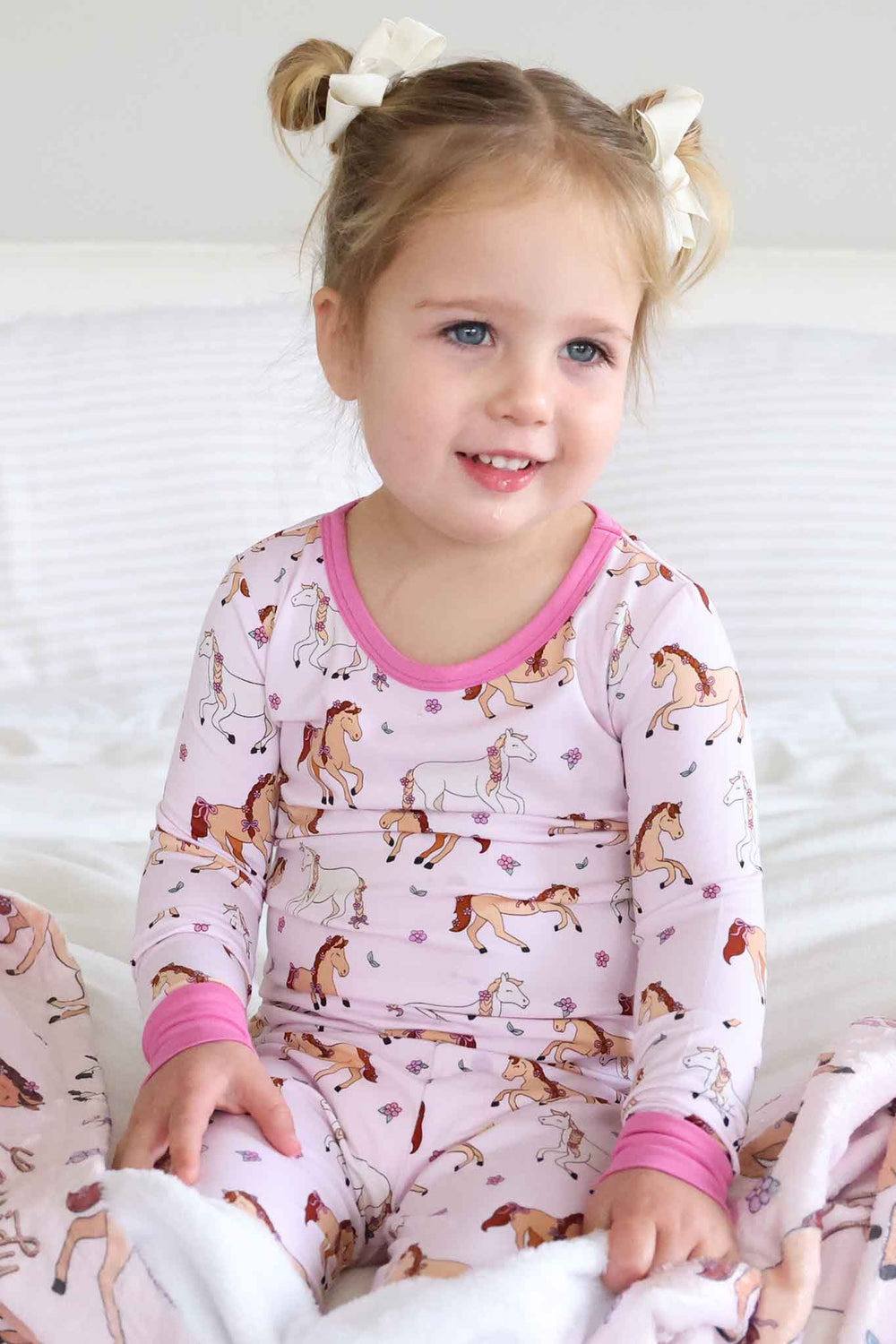 girl wearing pony club pink two piece pajama set with space buns 