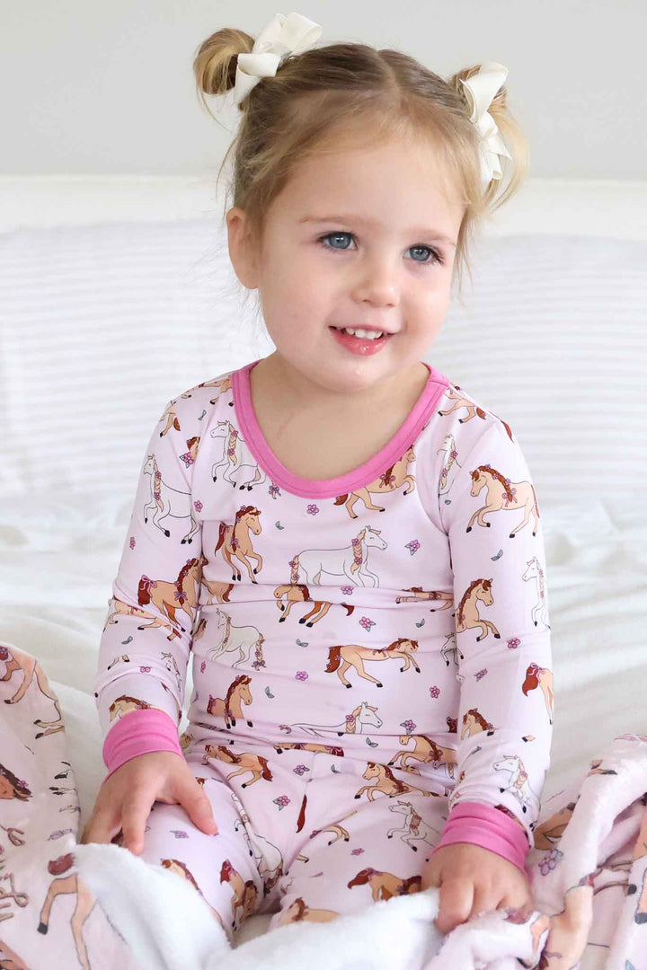 girl wearing pony club pink two piece pajama set with space buns 